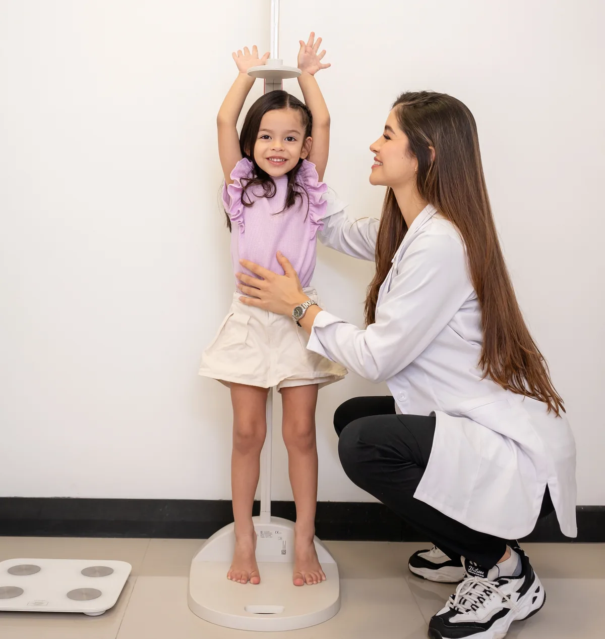 La Dra. Laura Mendoza tomando la talla de una niña en su consultorio